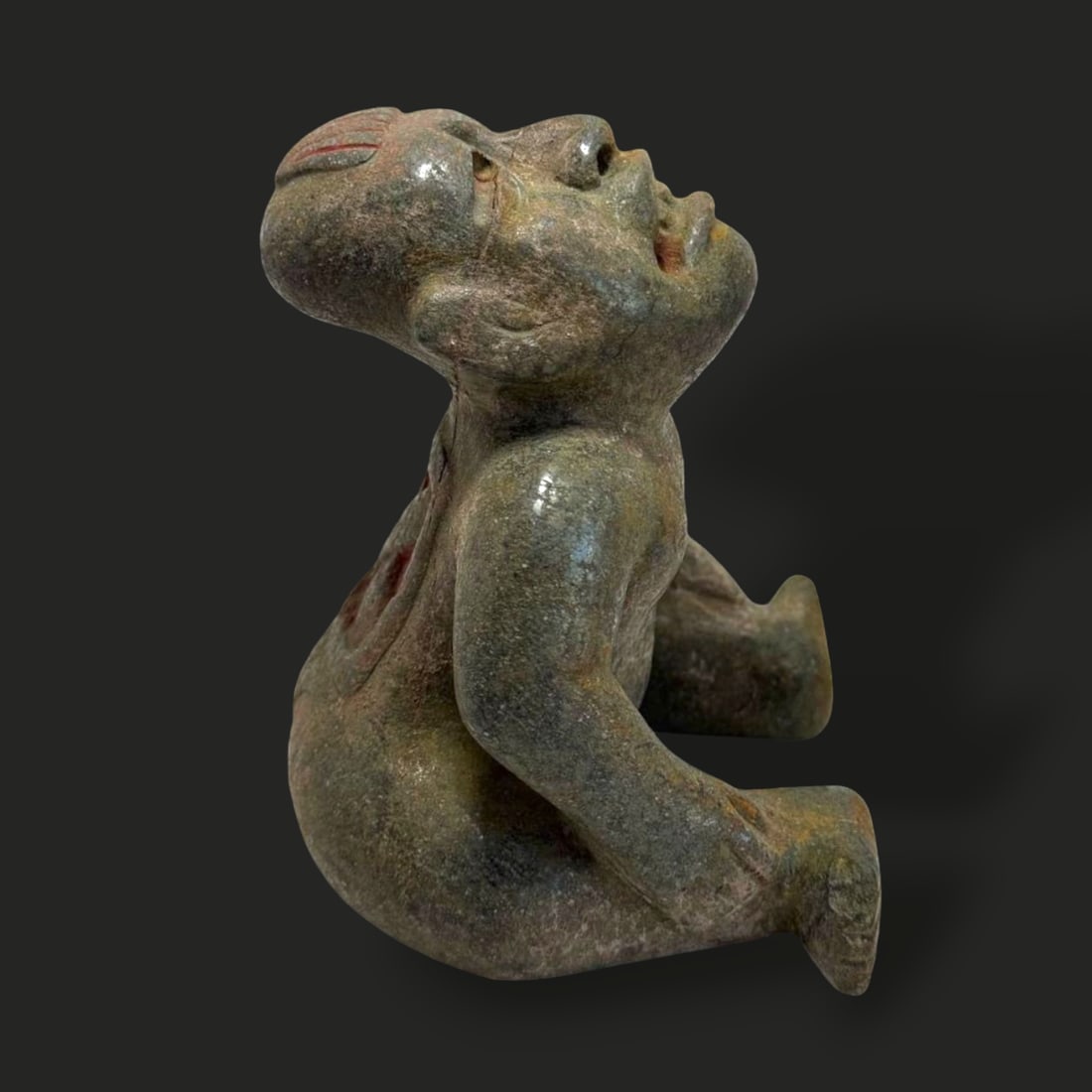Pre-Columbian Olmec green stone star gazer: Pre-Columbian Olmec green stone "Star Gazer" figure is a captivating representation of Olmec artistry and spiritual symbolism. Carved from green stone with natural weathering and subtle traces of red 