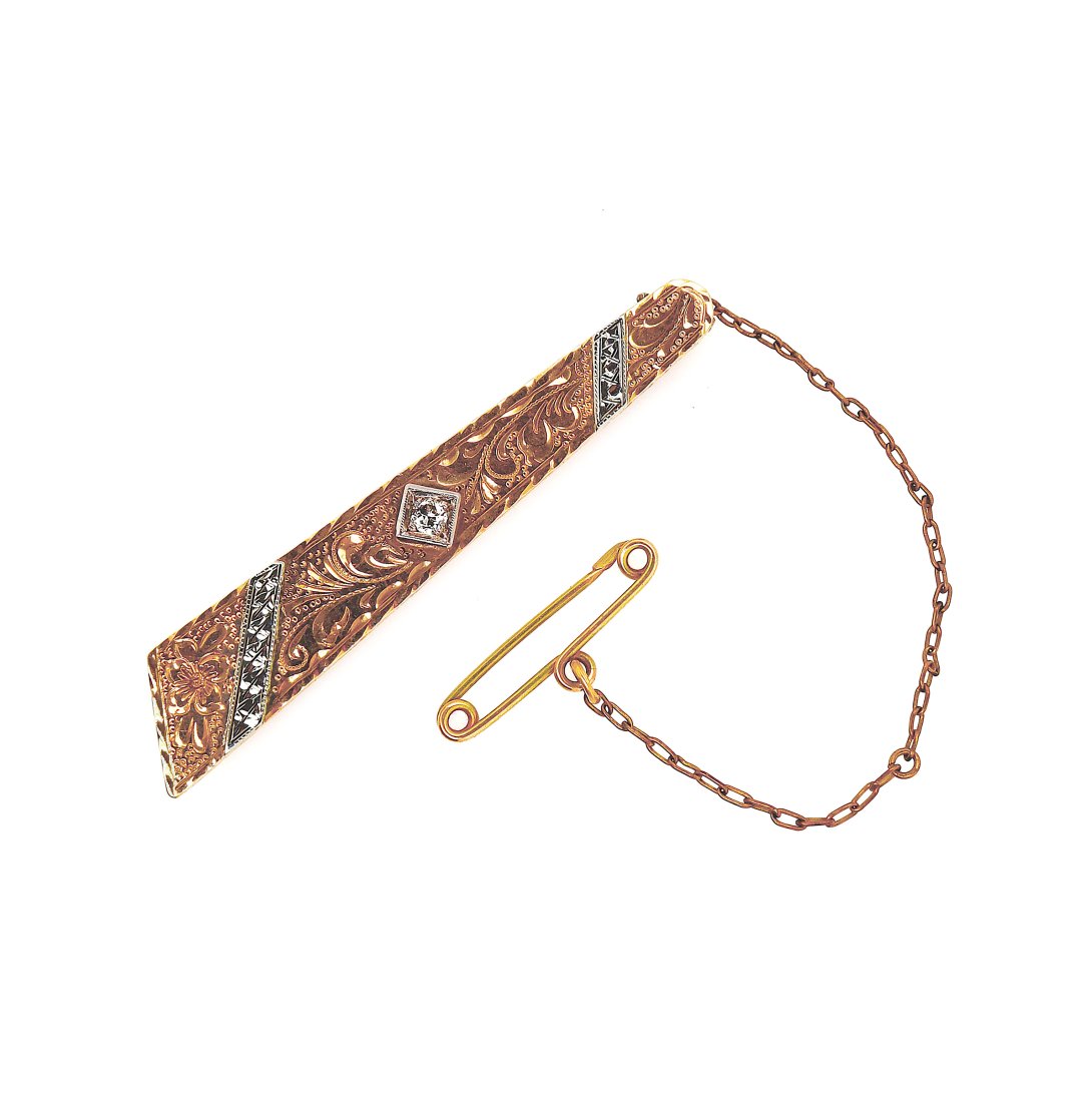 9CT Yellow And White Gold Diamond Antique Tie Clip: A 9ct yellow and white gold diamond antique tie clip. Features one 0.15ct old European cut diamond. Measure at 53mm in length by 6mm - 10mm in width and weight 5.69g. Secured by a clip with a safety p