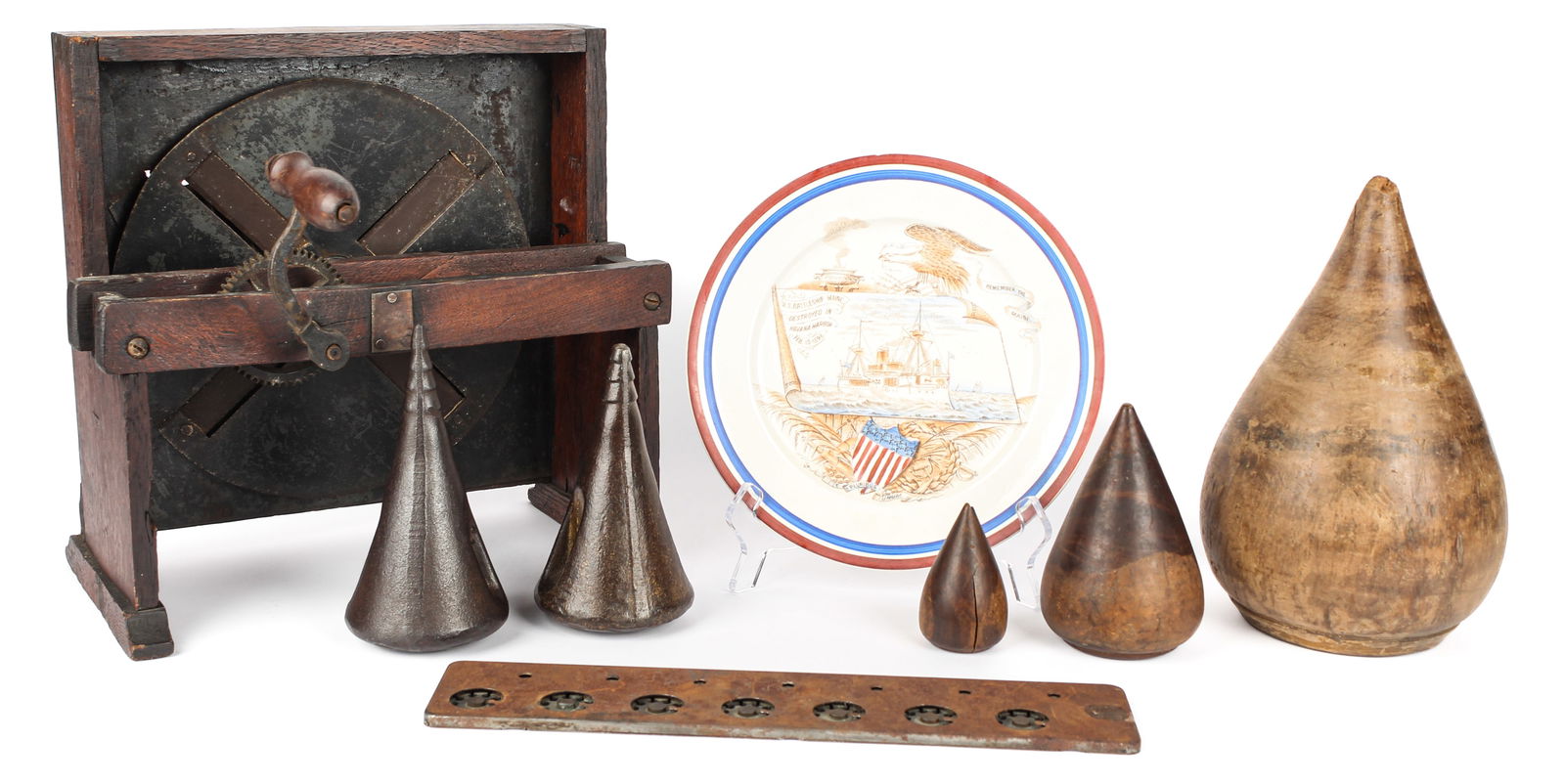Primitives: Description: Three antique wooden plumbers turnpins, two Oregon cast iron maul wedges, a "Lightning Calculator" adding machine, a primitive slicing machine, and a Battleship Maine plate. Type: Primit