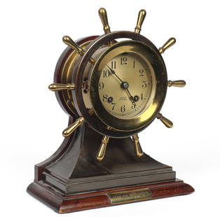 Chelsea Ship's Bell Mantel Clock: Description: A brass mantel or desk clock in the form of a ship's wheel, awarded to Durand Taylor in 1946. Type: Clock Materials: Brass, wood, metal Markings & Inscriptions: Marked Date: 1946 Maker