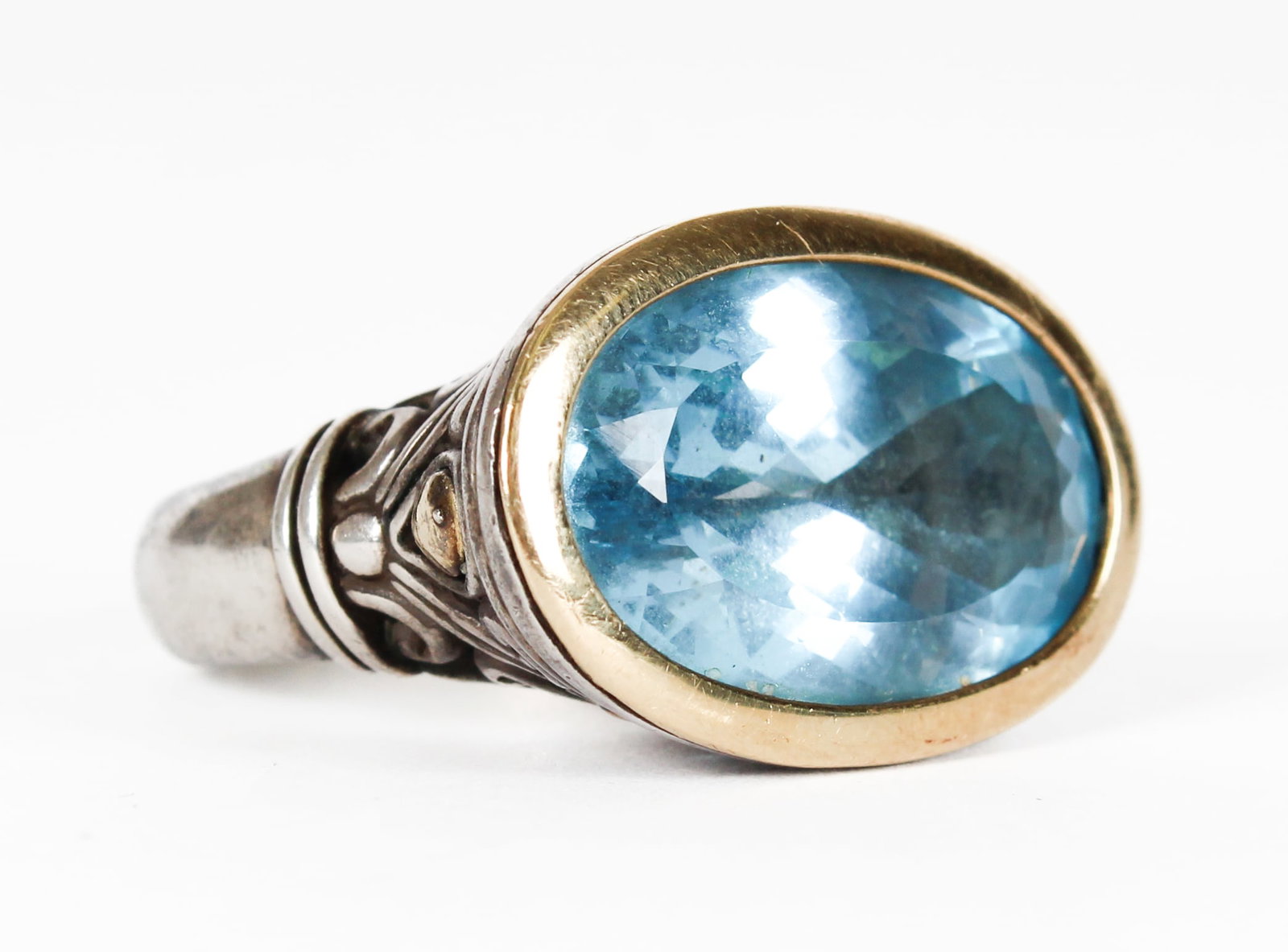 A Silver John Hardy Horizontal Set Blue Topaz Ring With 18k Gold Accents: Description: A silver John Hardy horizontal set blue topaz ring with 18k gold accents. Materials: Bue topaz, silver, goldMarkings & Inscriptions: 18k, 925, Thailand, JH mark Date: Late 20th - 21st cen