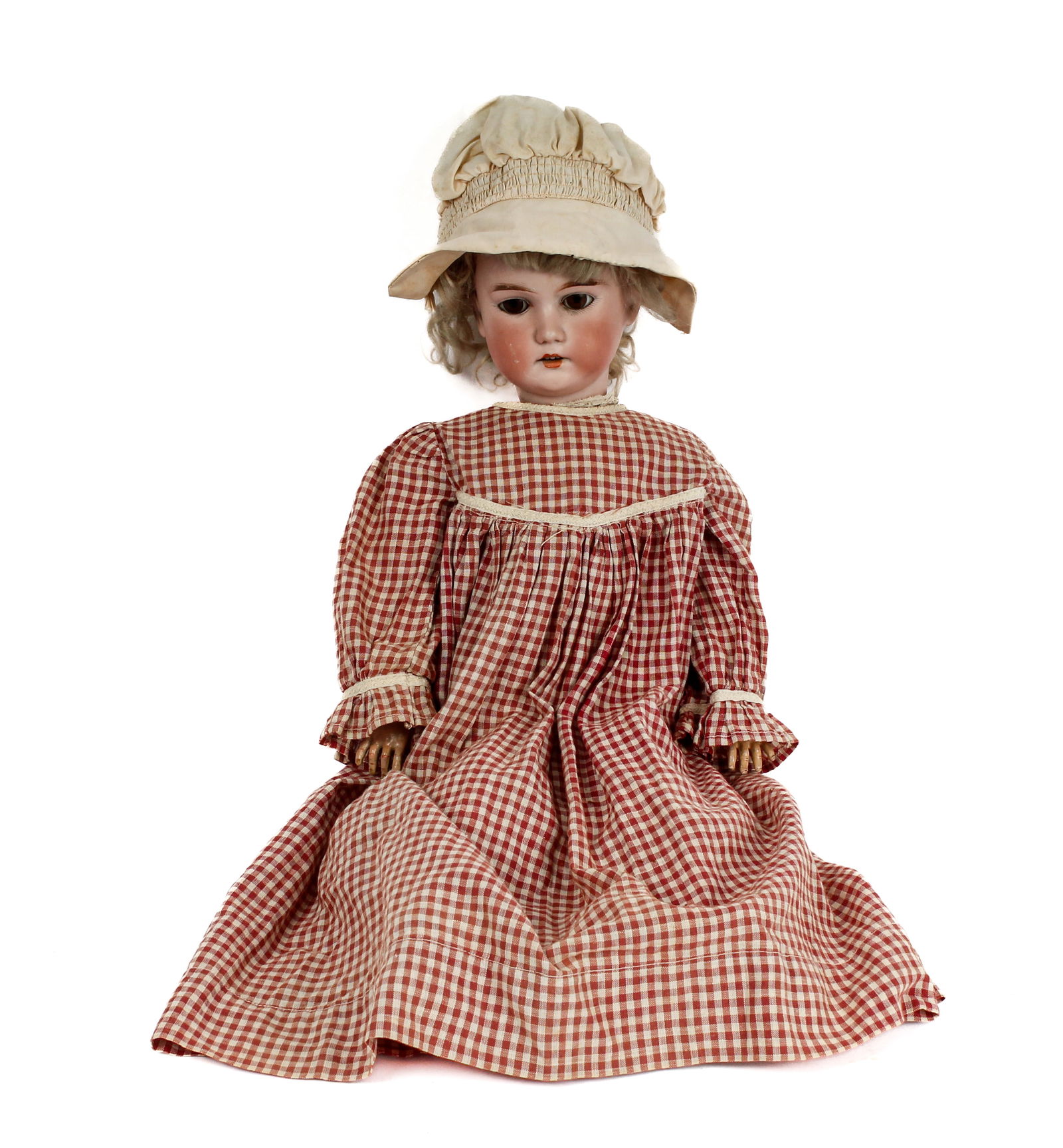 CM Bergmann Antique German Bisque Doll: Description: An antique CM Bergmann bisque doll with articulated limbs and moving eyes, wearing a gingham dress, bloomers, petticoat, undergarments, socks and shoes. Has brown eyes with painted eyelas