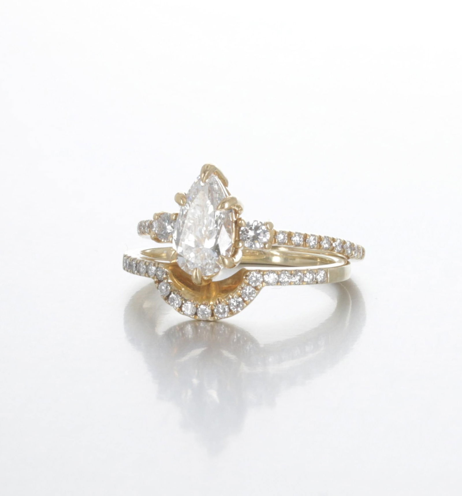 14K Brilliant Earth "Lyra" Diamond Wedding Ring Set: Description: A yellow gold Brilliant Earth " Lyra" two-piece wedding set in a modern setting. The main ring is 18K and contains one 1.01 CT. D color, VVS2 clarity, Pear-Brilliant cut natural diamond, 