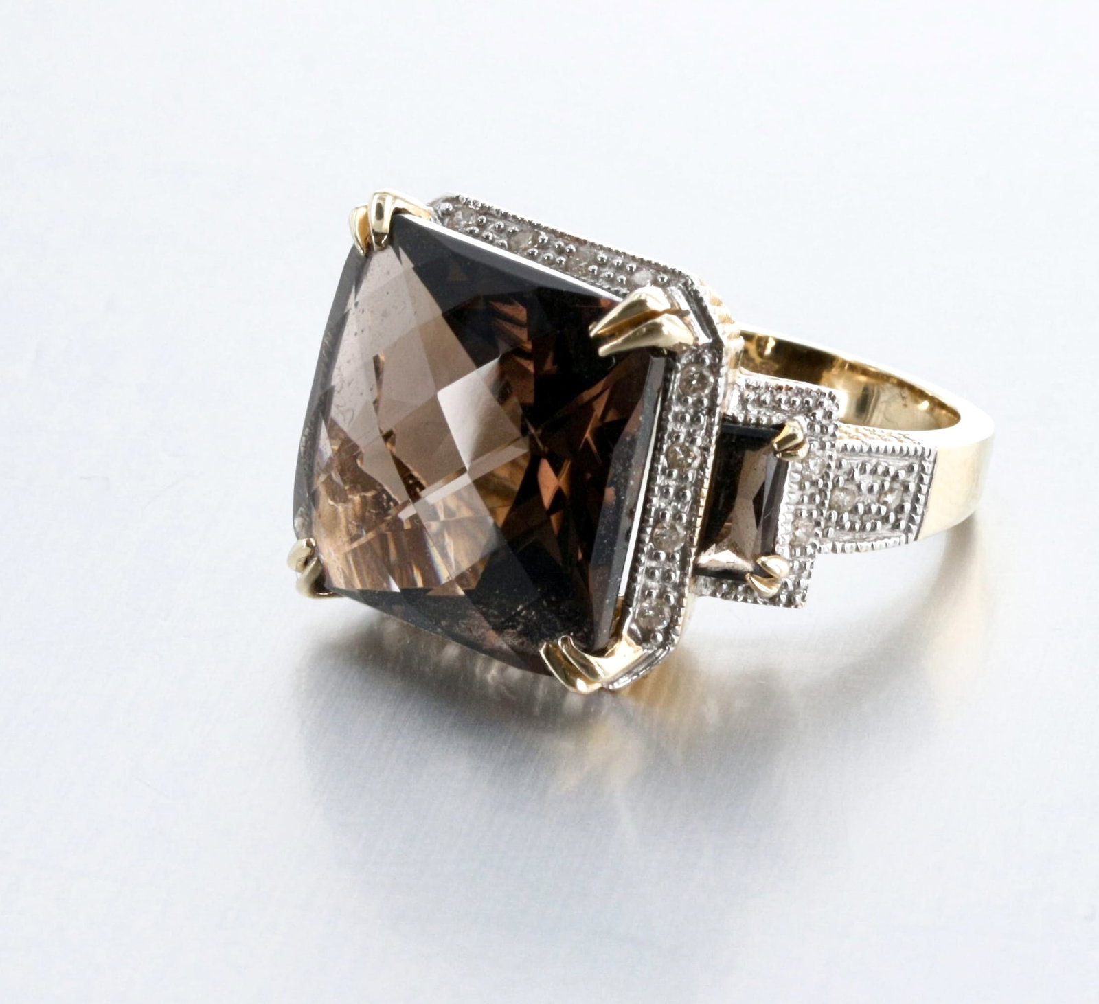 14K Gold Smoky Quartz and Diamond Ring: Description: A 14K Gold diamond-accented smoky quartz ring set with a square checker-cut and two baguette-cut smoky quartz gemstones; the center stone measures 15.08mm, set with 24 single-cut diamond 
