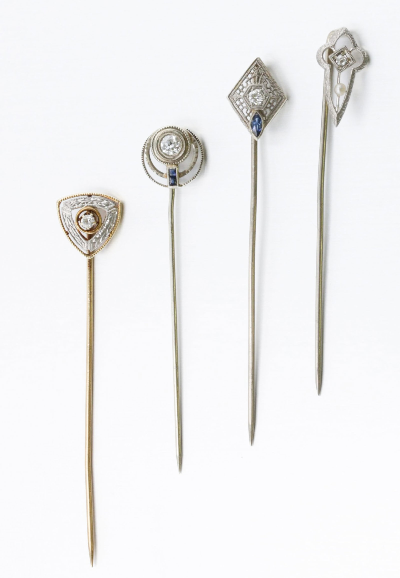 Gorup of Art Deco Gold and Diamond Stick Pins: Description: A group of four Art Deco stick pins. Consisting of one 18K Ostby & Barton Co. white gold stick pin set with one 0.15ct round Old European-Cut diamond and two synthetic French-cut sapphire