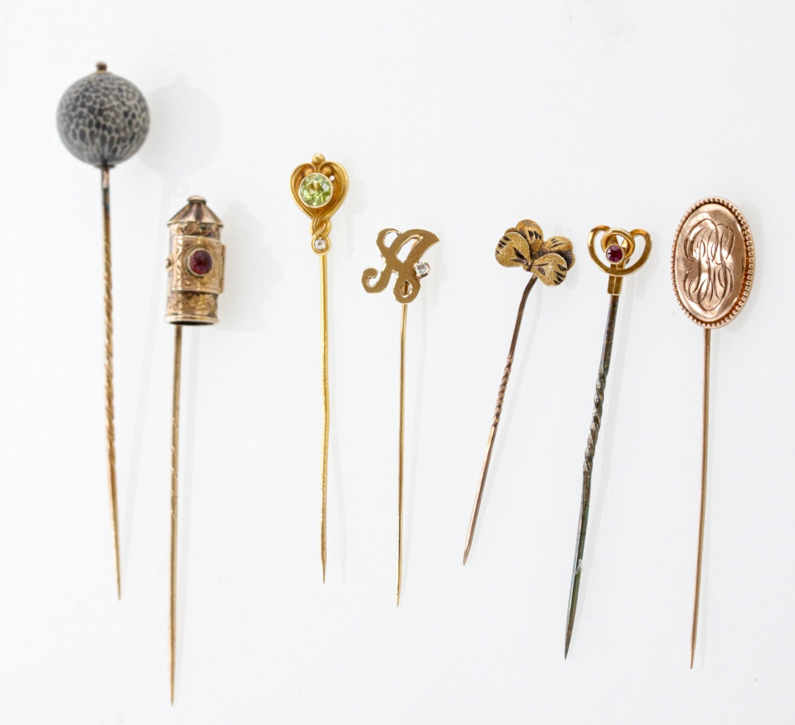 A Group of Seven Antique and Vintage Gold Stick Pins: Description: Group of Seven Antique and Vintage Gold Stick Pins, including a Wilcox & Co. peridot stick pin, signed WX Wilcox & Co., Providence, RI, circa 1915, stamped 14K; an oval-shaped stick pin w