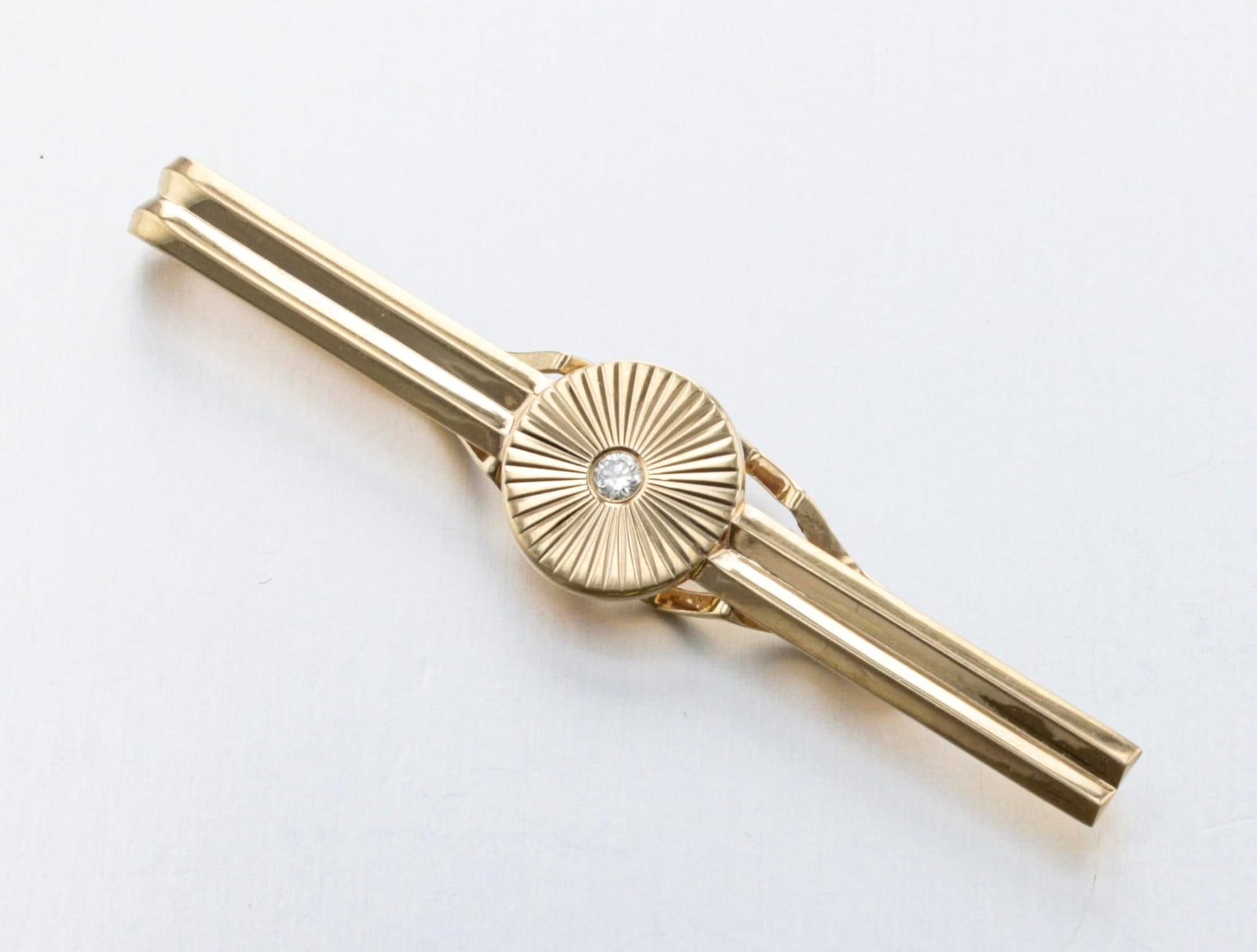 14K Gold and Diamond Tie Bar: Description: An Art Deco-style 14K diamond tie bar, designed as a fluted engine-turned sun ray-pattern centered by a flush-set diamond. Br>Markings & Inscriptions: Stamped "14K", maker's mark Date: Mi