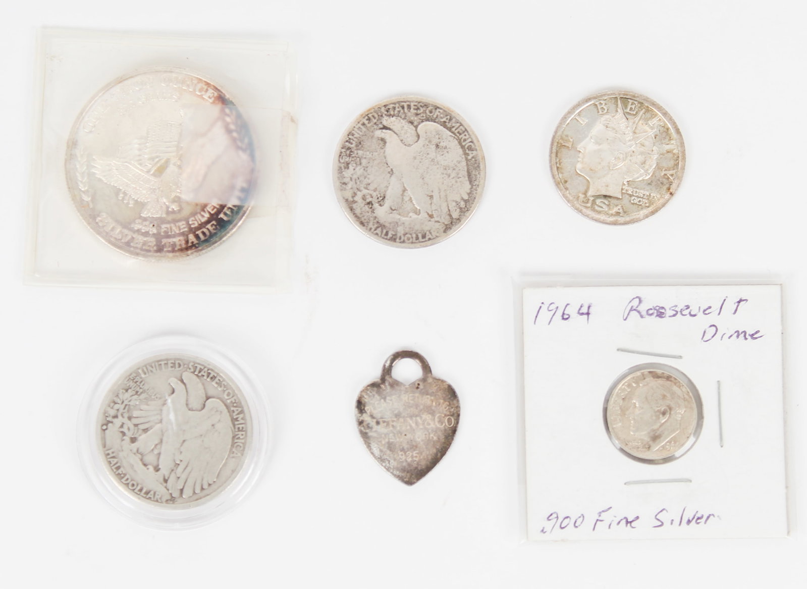 Collection of Silver Coins, Etc.: Description: A collection of silver coins, including a 1945 half dollar, a 2006 .999 silver Liberty Dollar, a Tiffany & Co. .925 silver heart shaped tag, a 1929 Liberty half dollar, a US Assay Office 