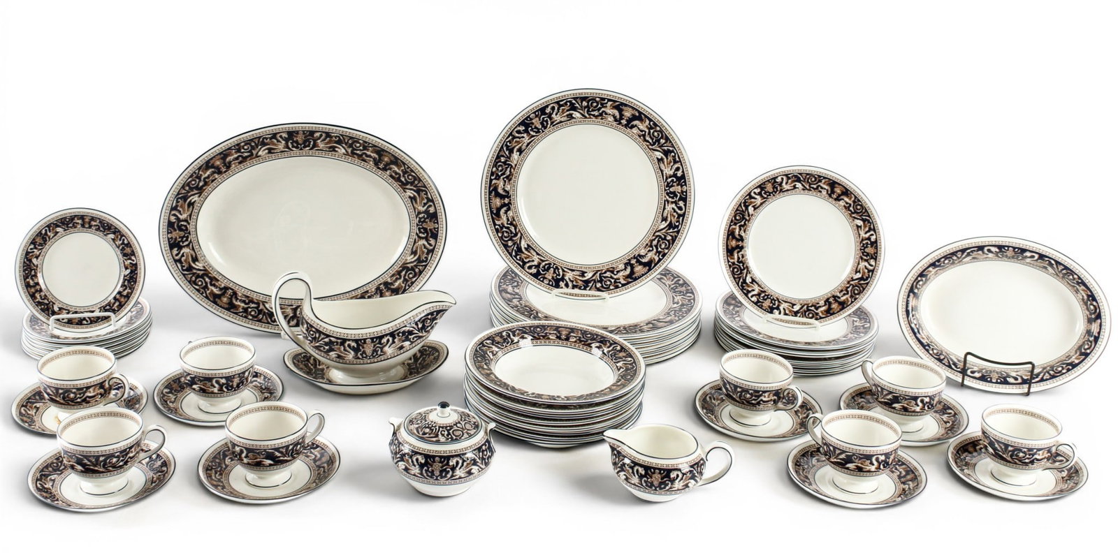 Wedgwood Florentine Dinner Service: Description: A porcelain service in the Florentine pattern by Wedgwood. Included are 8 teacups & saucers, 1 serving platter, 1 serving bowl, 1 gravy boat, 8 dinner plates, 1 cream & sugar, 8 bread pla