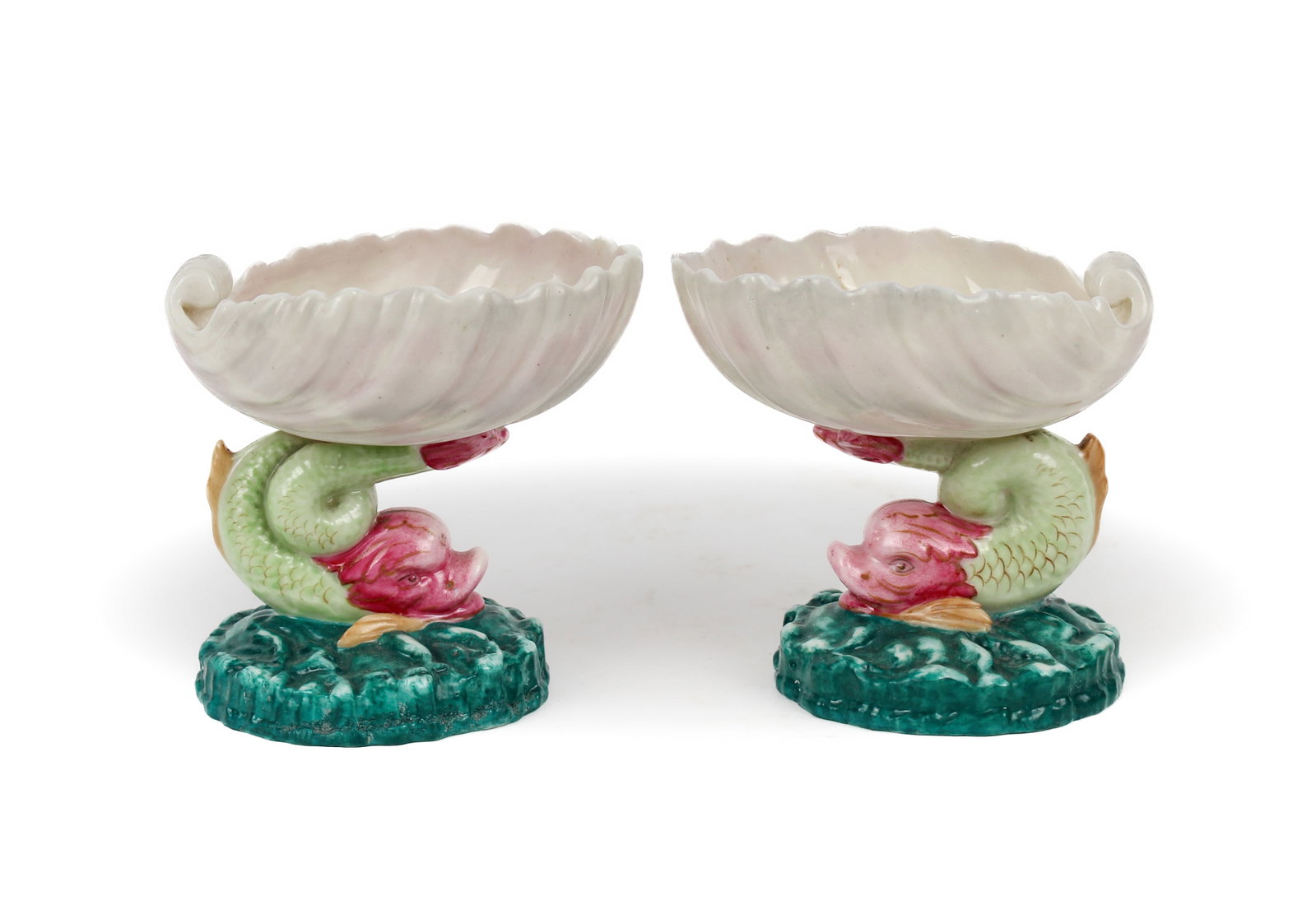 Royal Worcester Porcelain Dolphin & Shell Open Salts: Description: A pair of porcelain open salts, each in the form of a swimming dolphin suspending an iridescent shell from its tail. Additional Royal Worcester items from the estate of Stuart Brown will 