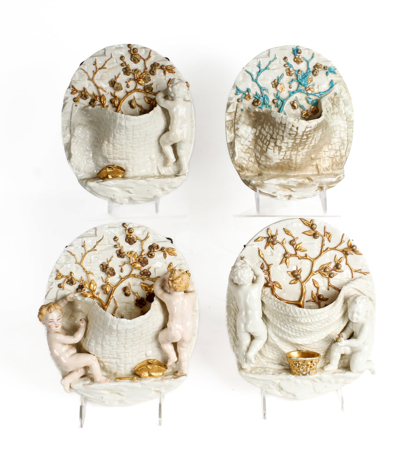 Four Royal Worcester Porcelain Wall Pockets, James Hadley: Description: Group of four Royal Worcester porcelain wall pockets designed by James Haldey. Three out of four wall pockets depicting putti or cherubs collecting fruits. Decorated in white and gold, on