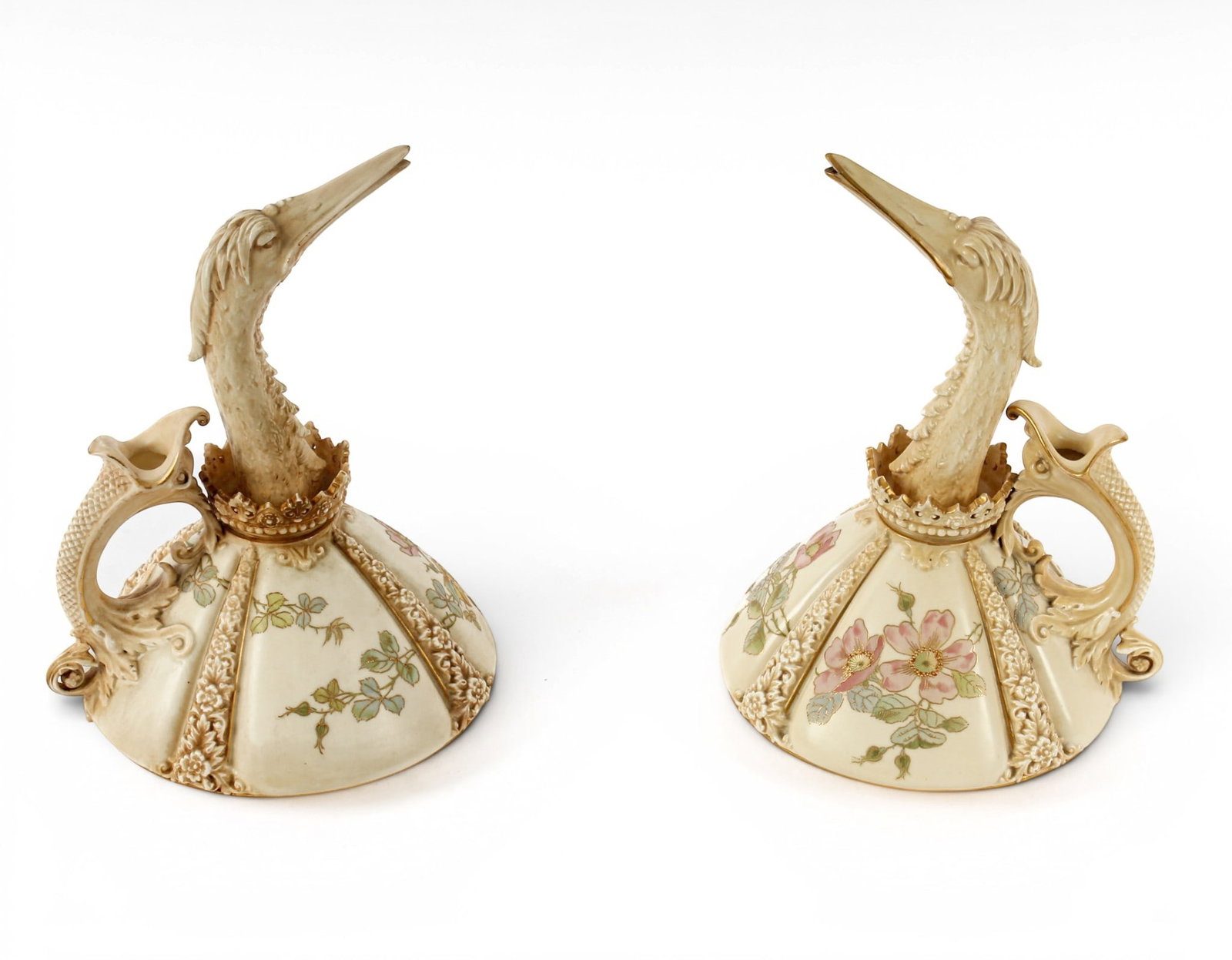 Pair of Royal Worcester Bird-Form Ewers: Description: Pair of Royal Worcester blush ivory porcelain ewers. Enameled and painted with blue, pink and yellow flowers. The spouts modeled in bird head form each with a stylized dolphin-form handle