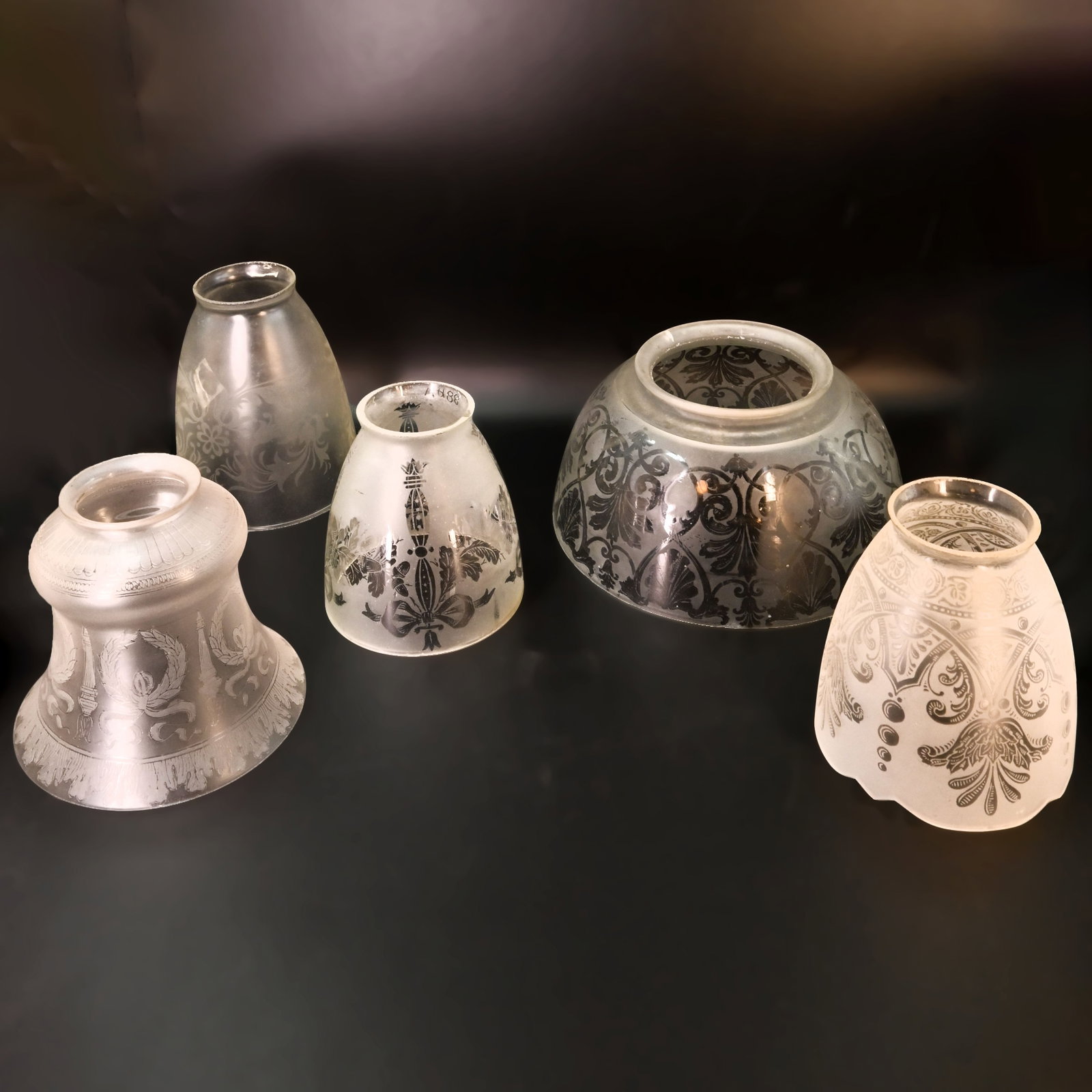 Group of five 2 1/4" fitter and one 4" fitter gas/electric mixed design etched glass shades: Group of four 2 1/4" fitter and one 4" fitter gas/electric mixed design etched glass shades. Left: 4 3/8" tall x 4 7/8" diameter. Middle Left: 5" tall x 4" diameter. Center: 4" tall x 4 " diameter. Mi