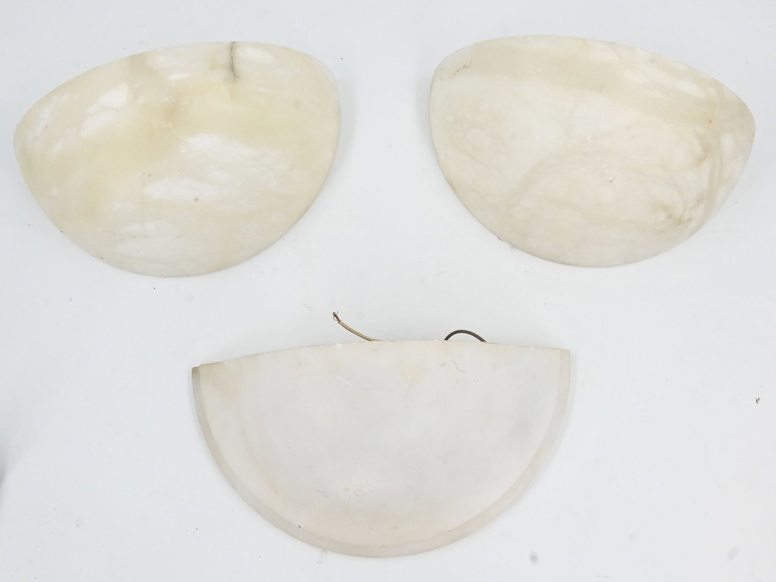 Set of three alabaster bowl sconces. Two match: Set of three alabaster bowl sconces. Two match. One medium edison socket per fixture. Pair dimension: 5.5" tall x 11" wide x 5.5" projection. Single dimensions: 4.5" tall x 12" wide x 6" projection. T