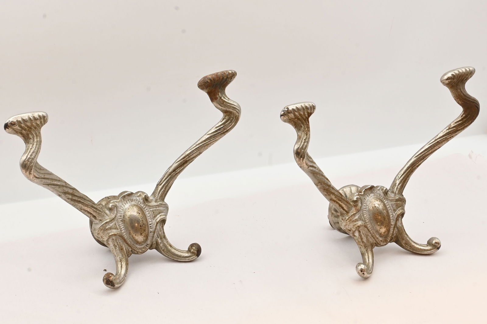 Pair of nickel plated art nouveau coat hat hooks: Pair of nickel plated art nouveau coat hat hooks. Condition: Age Consistent. Material: Cast Brass, Nickel Plated. Dimensions: 5.25 inches tall x 7 inches wide x 3.5 inch projection. This item is offer