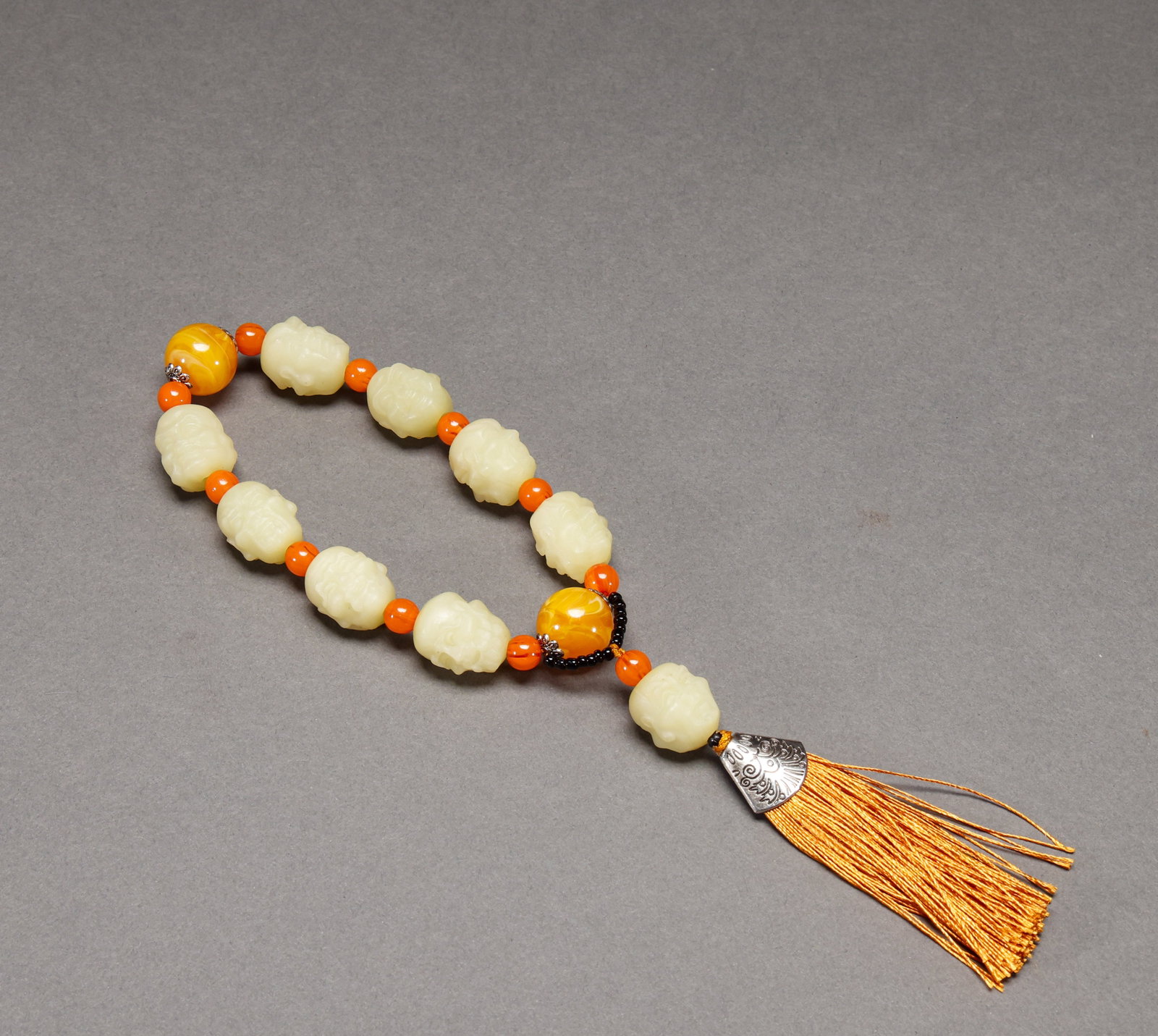 Qing Dynasty Huangyu Luohan Hand String: Qing Dynasty yellow jade arhat bracelet, yellow jade carved arhat head bracelet with beeswax spacer beads and tassel, fine carving. Height: 2cm, Width: 1.7cm, Weight: 100g.