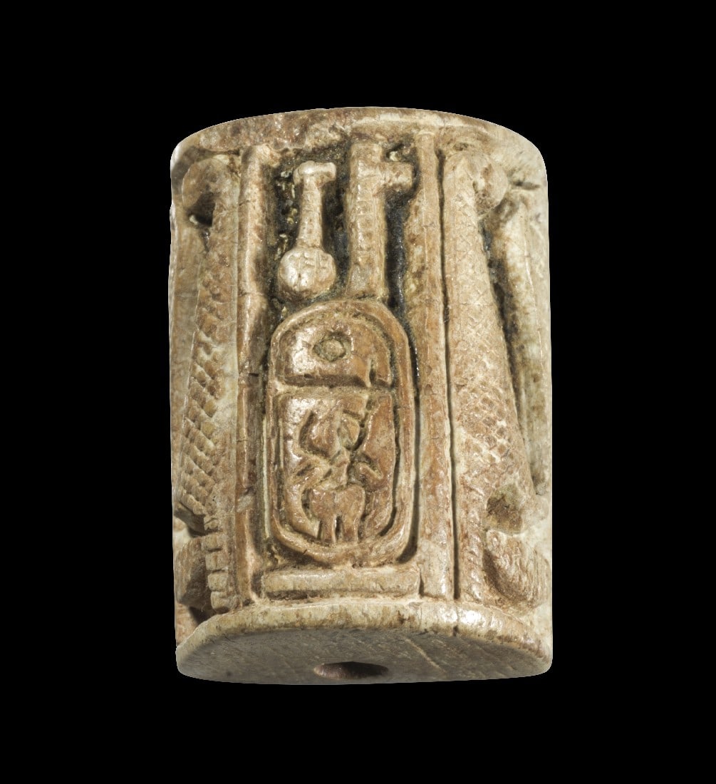 Amulett mit dem Thronnamen Amenophis' II.: Amulet in the shape of a halfcylinder made of light brown steatite with longitudinal drilling, H 2cm. On the top: the throne name of Amenophis II (= Aa-cheperu-Re) in cartouche and Imen/Amun in enigma