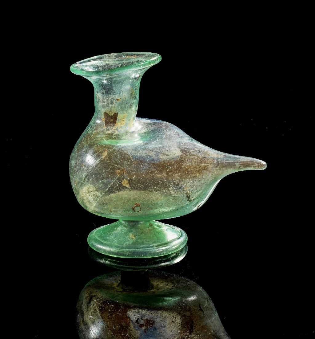 Wunderschönes Gefäß in Vogelform.: Bird-shaped funnel. Eastern Mediterranean, 1st - 2nd century AD. H 7,7cm, L 8,5cm. Green translucent glass. Bag-shaped body with foot, tall cylindrical neck and broad rim. Attractive iridescence, inta