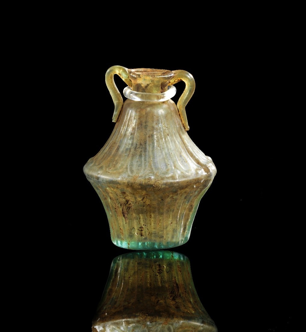 Seltener bikonischer Amphoriskos.: Roman biconical amphoriskos of colorless glass with fine ornament. About 1st century AD. Tiny fissure in the neck, otherwise intact. Seltener bikonischer Amphoriskos. Römisch, ca. 1. Jh. n. Chr. H oh