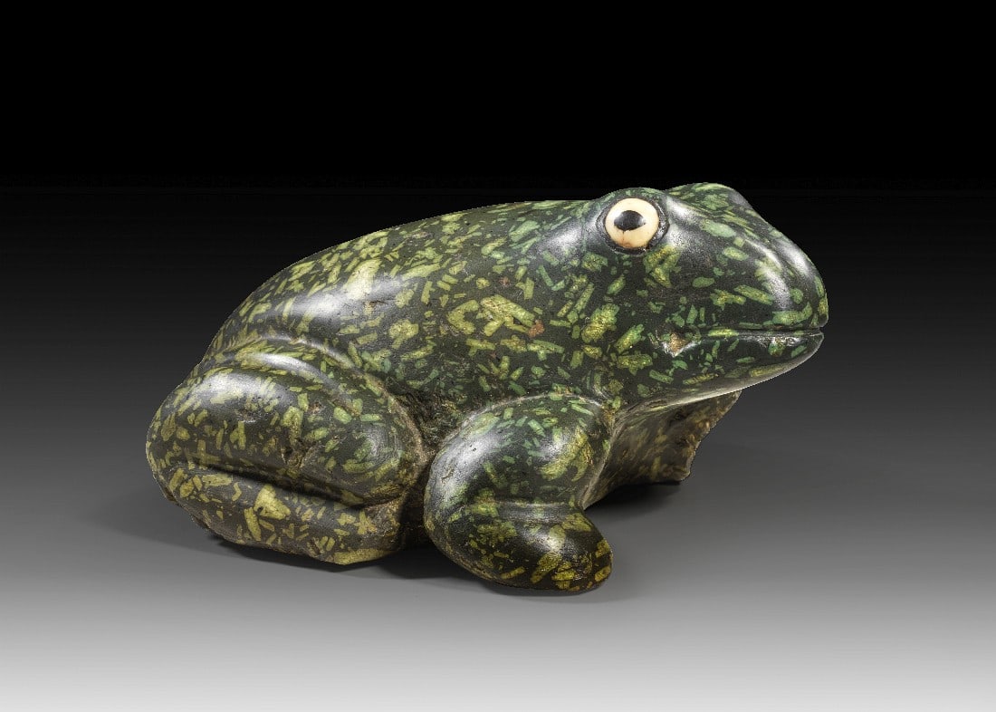Frosch aus Porfido verde antico.: Frosch aus Porfido verde antico. Römische Kaiserzeit. 1. - 3. Jh. n. Chr. L 22cm, B 16,5cm, H 11cm. Grüner Porphyr. Hockender Frosch mit leicht nach rechts gewandtem Kopf. Die Augen sind in weißem