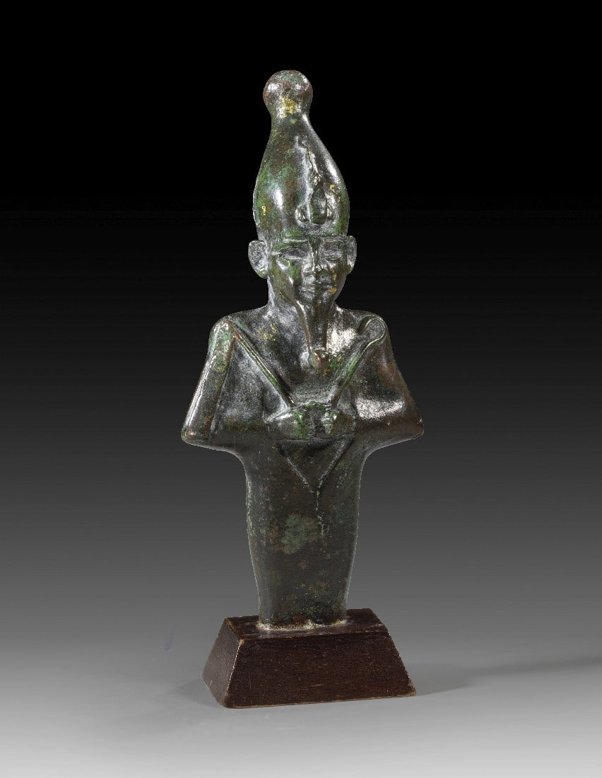 Bronzestatuette des Osiris.: Bronzestatuette des Osiris. 3. Zwischenzeit bis Spätzeit, ca. 1070 - 664 v. Chr. H 13,2cm, mit Holzsockel 15,2cm. Bronzevollguss. Mumiengestaltige Figur des Gottes Osiris mit Atef-Krone, Uräus und