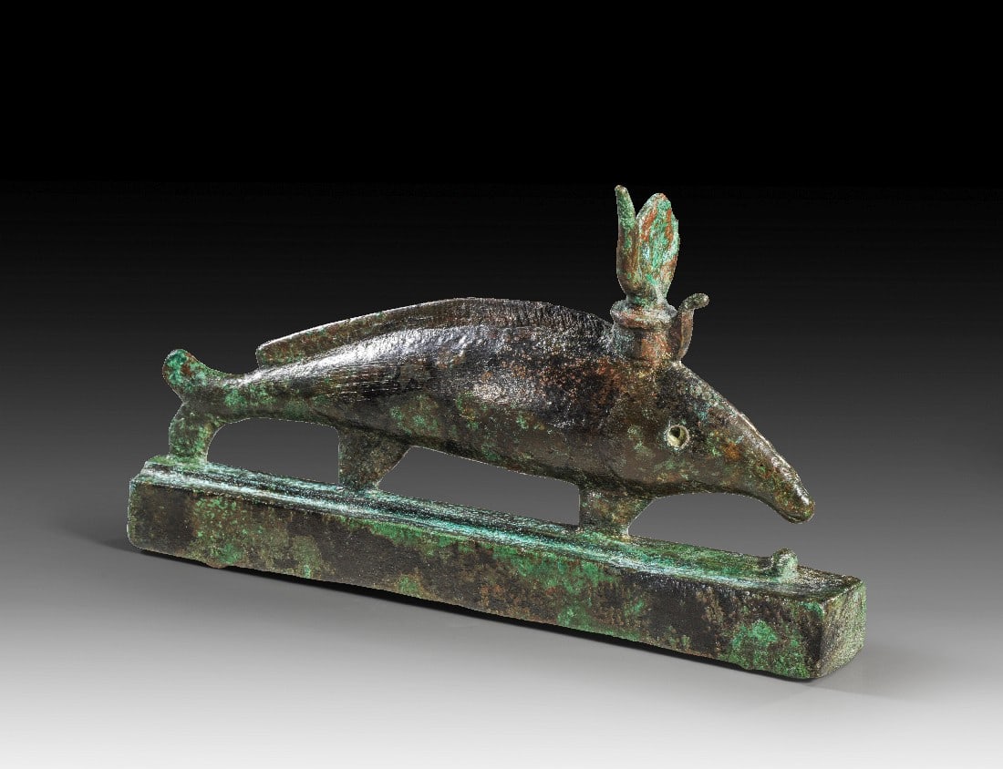 Oxyrhynchos-Fisch.: Oxyrhynchos-Fisch. Spätzeit, 1. Jt. v. Chr. L 17,5cm, H 10,5cm. Bronzevollguss. Nilhecht mit Kuhgehörn, Sonnenscheibe und Uräus auf einem integrierten "Schlitten", der mit der Basis fest verbunden