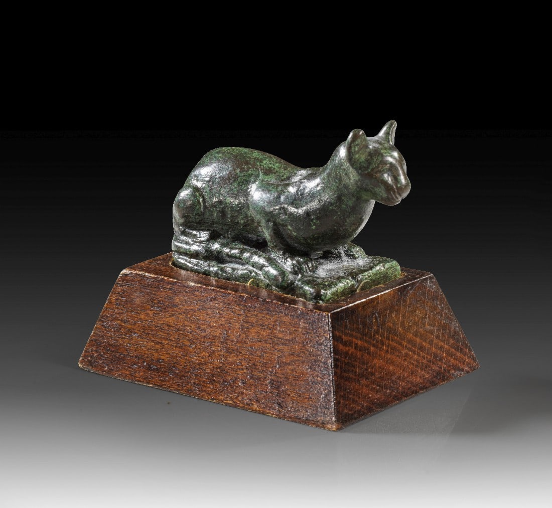 Katze.: Katze. Spätzeit - Ptolemäische Periode, 664 - 30 v. Chr. L 5cm, H 3,3cm, mit Sockel 5,2cm. Schwere Bronzefigur (110.85g) einer liegenden Katze, dem heiligen Tier der Göttin Bastet. Grüne Patina,