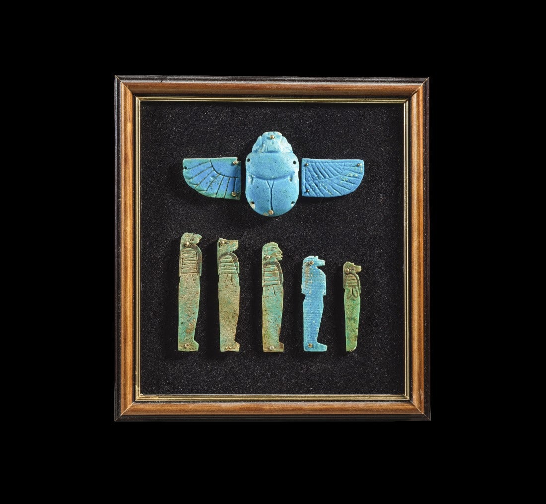 Mumienapplikationen.: Mumienapplikationen. Spätzeit, 1. Jt. v. Chr. In Holzrahmen mit Nägeln auf mit schwarzem Samt bezogener Sperrholzplatte befestigt. Geflügelter Skarabäus aus hellblauer Fayence (B 12cm, L 5,5cm),