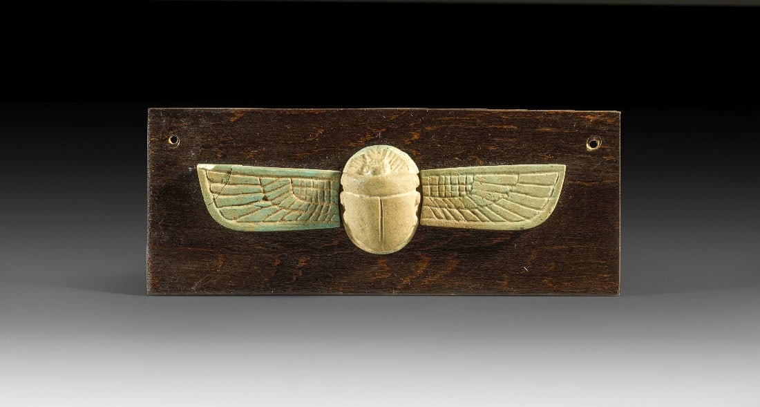 Geflügelter Skarabäus.: Geflügelter Skarabäus. Spätzeit, ca. 664 - 332 v. Chr. L gesamt 10cm, L Käfer 2,1cm. Beige bis türkise Fayence. Binnenzeichnung geritzt. Spitze des linken Flügels gebrochen, montiert auf eine