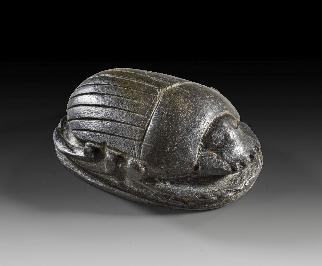 Herzskarabäus.: Herzskarabäus. Spätzeit, ca. 724 - 332 v. Chr. L 5,5cm. Schwarzer Serpentin. Naturalistisch gestalteter Skarabäus auf Plinthe, Rückenflügel in feinem Strichdekor, die Unterseite glatt. Intakt.