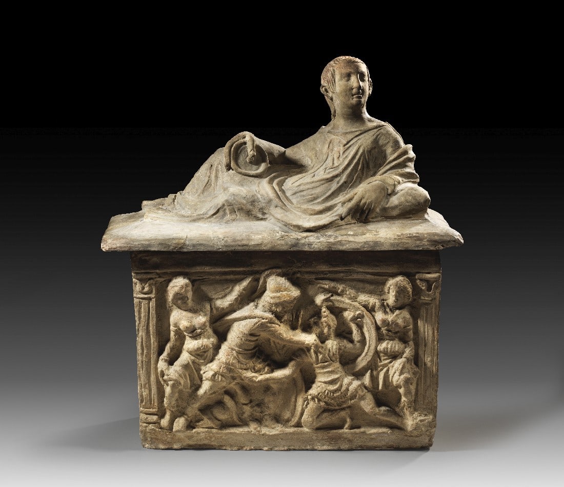 Etruskische Aschenkiste.: Etruskische Aschenkiste. 2. Jh. v. Chr. B max. 46,5cm, H mit Deckel 46,5cm. Hellbraune Terrakotta. Bildfeld und Deckelfigur aus Matrizen geformt. Auf dem Deckel vollplastisch ein seitlich lagernder