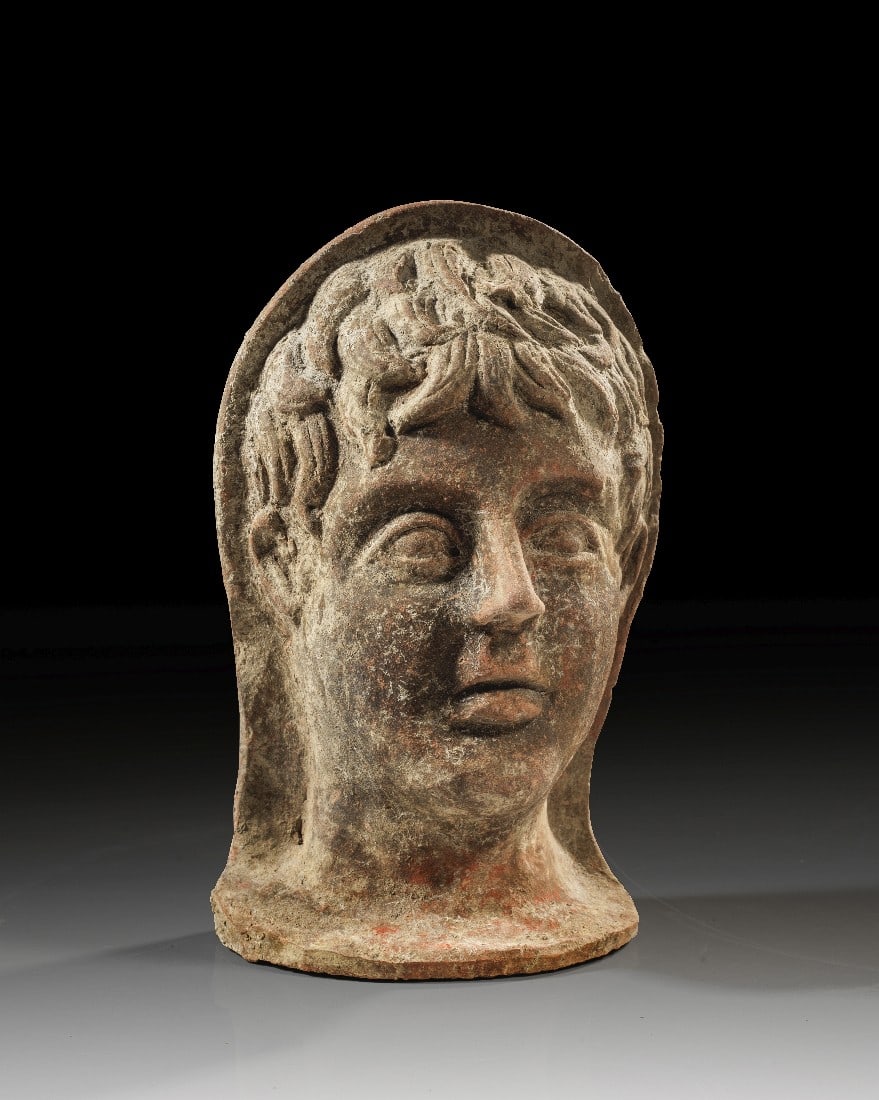 Etruskischer Votivkopf eines jungen Mannes.: Etruskischer Votivkopf eines jungen Mannes. 300 - 250 v. Chr. H 28,6cm. Matrizengeformt, aus rötlichem Ton mit dunkelbraunem Überzug. Schmaler Kopf eines Jünglings capite velato mit klassischer