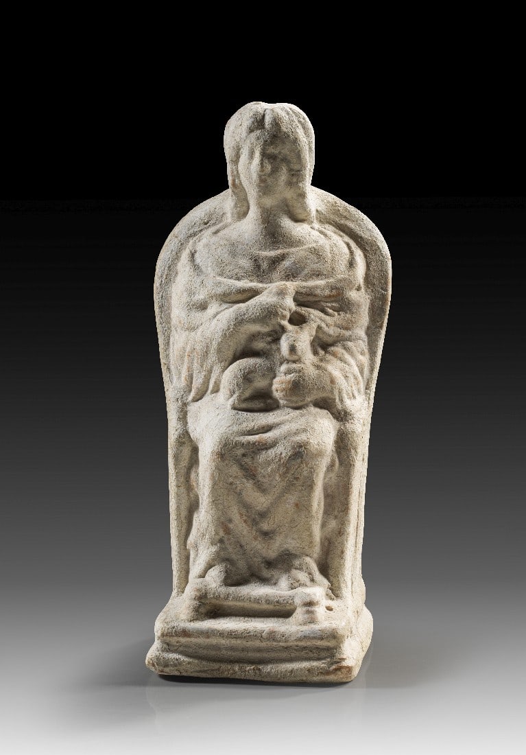 Thronende Kybele.: Thronende Kybele. Römisch, wohl Severerzeit. Ende 2. - Anfang 3. Jh. n. Chr. H 18,5cm. Hellroter Ton mit weißer Versinterung. Sitzende Frau auf einem Thron mit hoher, gebogener Rückenlehne und