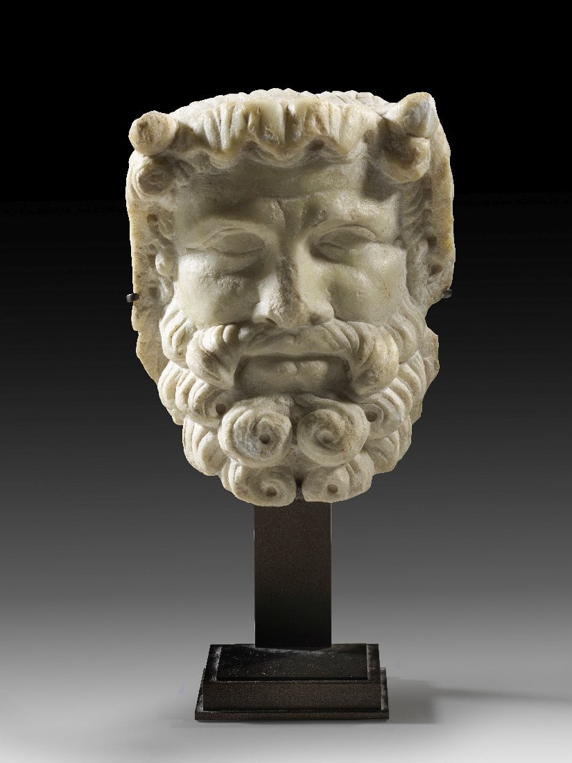 Hermenkopf des Dionysos.: Hermenkopf des Dionysos. Römische Kaiserzeit, 1. - 3. Jh. n. Chr. H 12,5cm. Weißer, feinkristalliner Marmor. Reliefartiger Einsatzkopf für eine Herme. Darstellung eines bärtigen Gottes mit