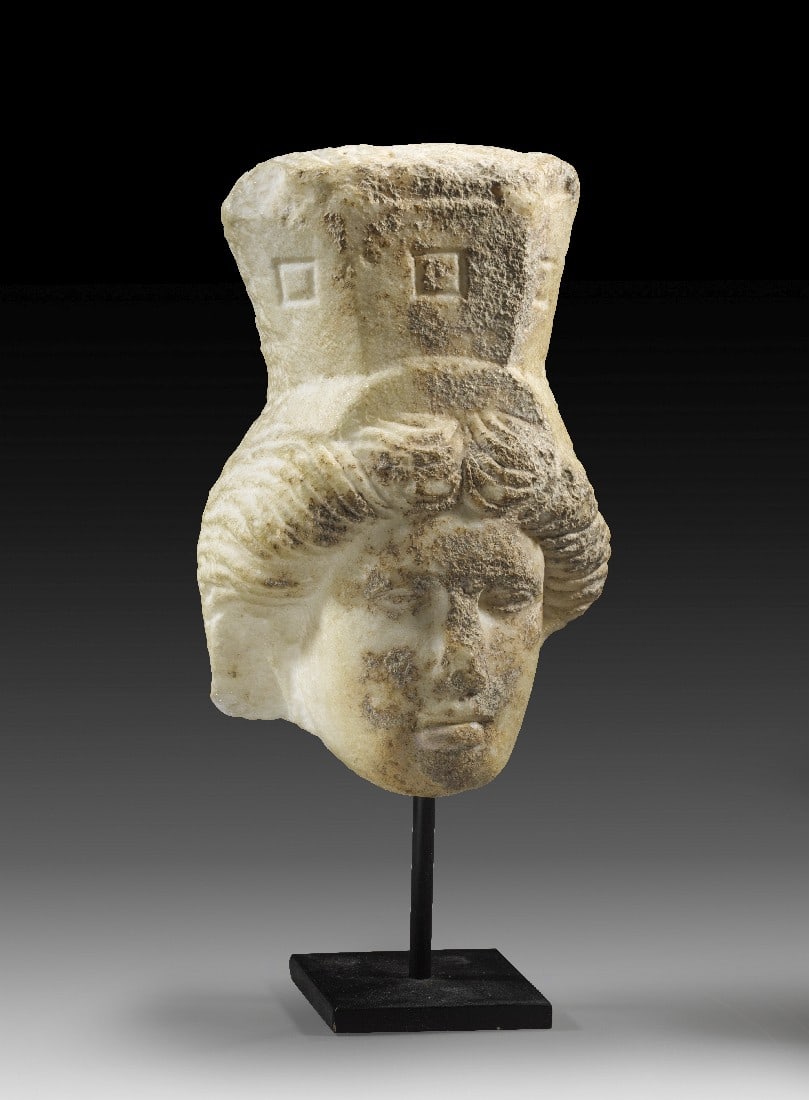 Kopf einer Stadtgöttin mit Mauerkrone.: Kopf einer Stadtgöttin mit Mauerkrone. Spätrömische Kaiserzeit, 4. Jh. n. Chr. H 16,9cm und mit Ständer 23cm. Feinkristalliner weißer Marmor. Frontaler Kopf von einem Relief der Göttin mit