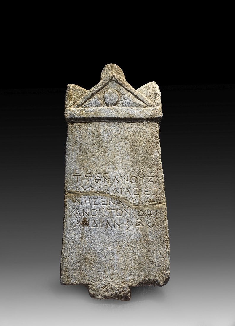 Grabstein mit Giebel und griechischer Inschrift.: Grabstein mit Giebel und griechischer Inschrift. Römisch, östliches Mittelmeergebiet, 2. - 3. Jh. n. Chr. H 66,5cm, B unten 30,5cm, T 7,5cm. Marmor. Platte, deren Längskanten leicht konisch