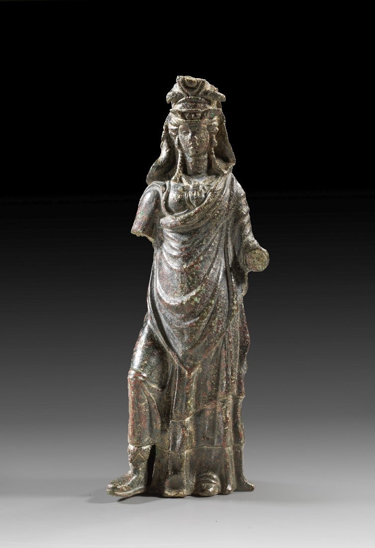 Polytheistische Göttin.: Polytheistische Göttin. Ende 2. - 3. Jh. n. Chr. H 17,5cm. Hohlguss. Frauengestalt in langen Gewändern mit verschiedenen Attributen: Krone der Isis, Stirnflügel der Musen, Ägis der Athena und