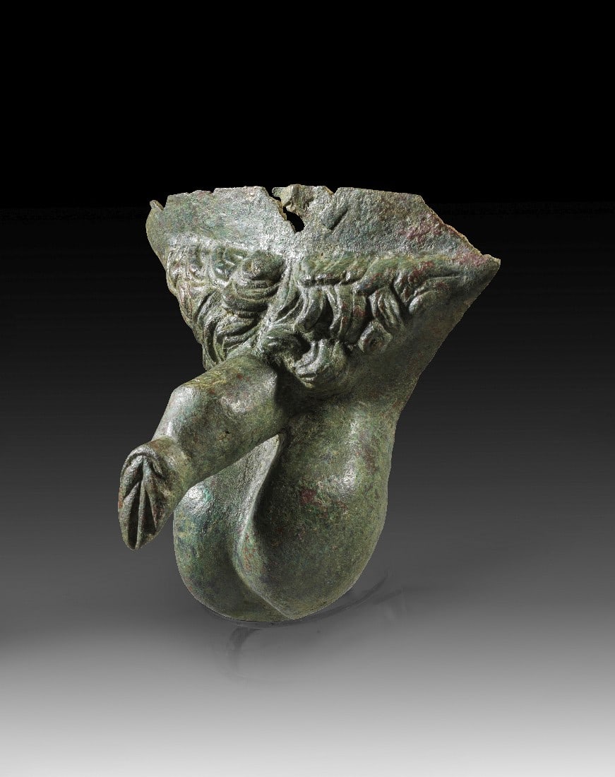 Männliches Geschlecht.: Männliches Geschlecht. Römische Kaiserzeit, 1. - 3. Jh. n. Chr. B 15cm, H 13cm. Hohlguss. Separat gefertigtes Fragment einer Bronzestatue. Schöne grüne Patina. Am oberen Rand kleinere Ausbrüche.