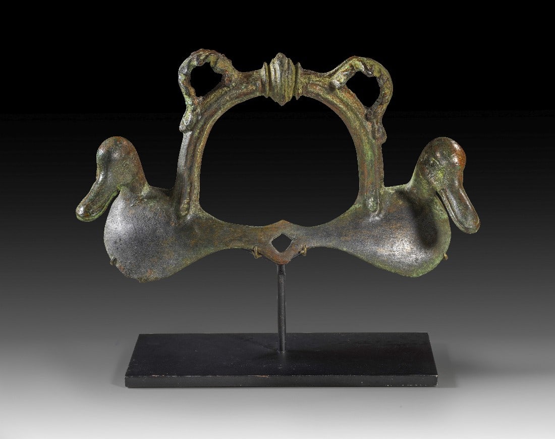 Großer Bronzehenkel mit Entenköpfen.: Großer Bronzehenkel mit Entenköpfen. Römisch, 1. Jh. v. Chr. - 1. Jh. n. Chr. B 21,2cm. Vollguss. Profilierter Bügelhenkel mit Akanthusblättern und zwei Entenköpfen für ein großes Becken.