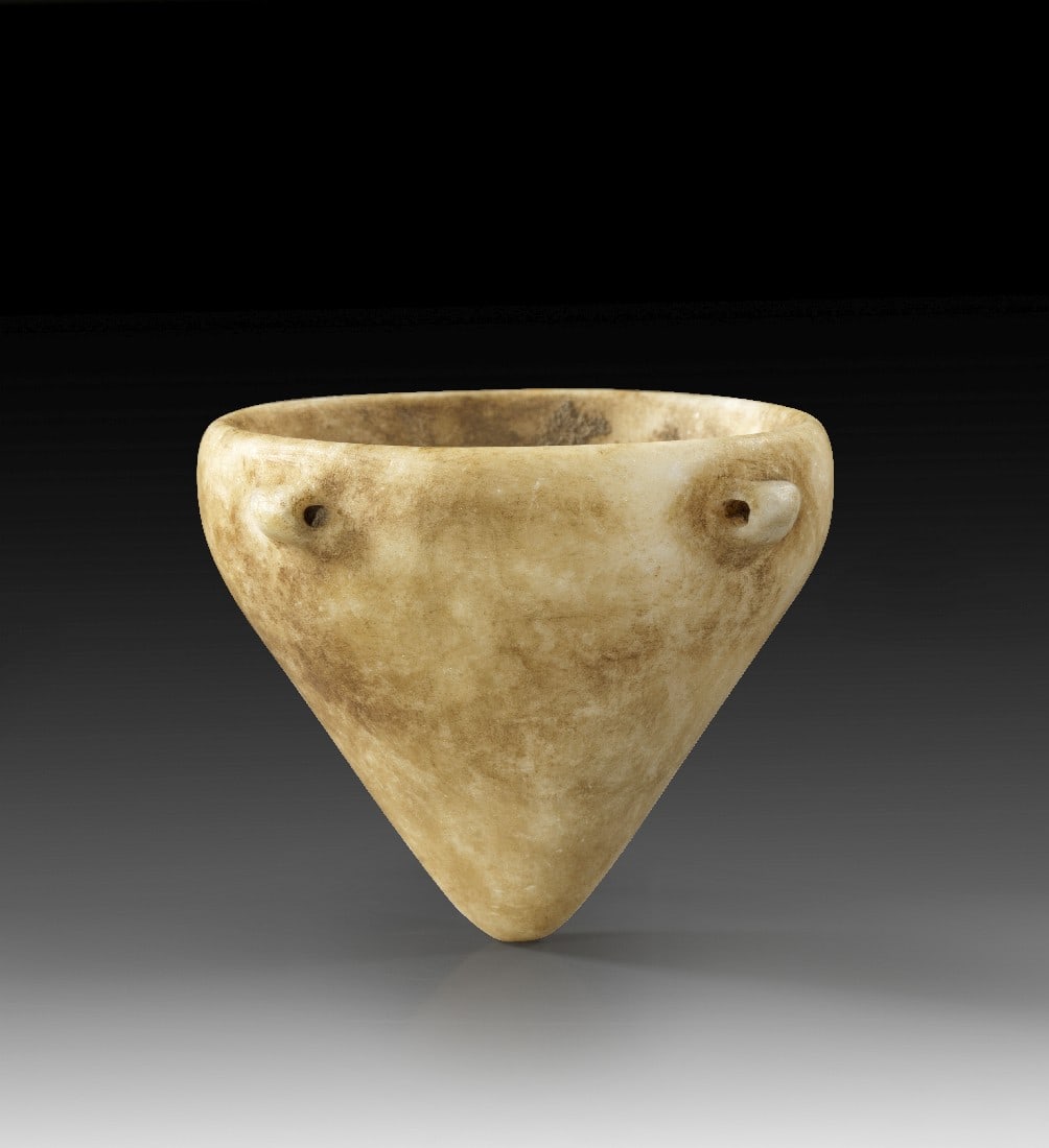 Miniaturgefäß mit Schnurösen.: Miniaturgefäß mit Schnurösen. Neolithisch, um 3000 v. Chr. H 6cm, ø 6,5cm. Marmor. Kegelförmig mit vier Schnurösen auf dem vertikalen Rand. Innen Reste von Sinter, intakt. Provenienz: Ex