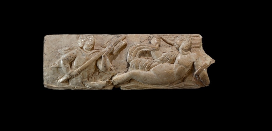 Relief mit Triton und Nereide.: Relief mit Triton und Nereide. Romano-ägyptisch, 3. Jh. n. Chr. L 11,5cm, B 3,9cm. Bein. Rechts lagert eine nackte Nereide, die in der Rechten einen Teil des sich bauschenden Gewands hält, links