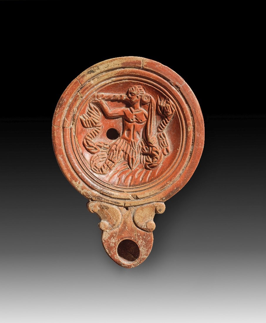 Römische Tonlampe mit Triton.: Römische Tonlampe mit Triton. Frühe Kaiserzeit, 1. Jh. n. Chr. L 12,8cm, ø 9,2cm. Loeschcke Typus IV aus hellbraunem Ton mit rot- bis dunkelbraunem Überzug. Auf dem Spiegel ein wunderschöner,