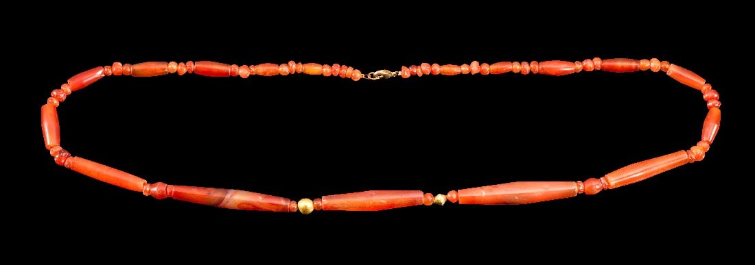 Kette aus Karneolperlen.: Kette aus Karneolperlen. Westasiatisch, 2. Jt. v. Chr. L 71cm. Aus bikonischen Röhrenperlen und kugeligen Perlen sowie zwei Goldperlen. Tragbar! Modern aufgefädelt mit Verschluss, intakt.