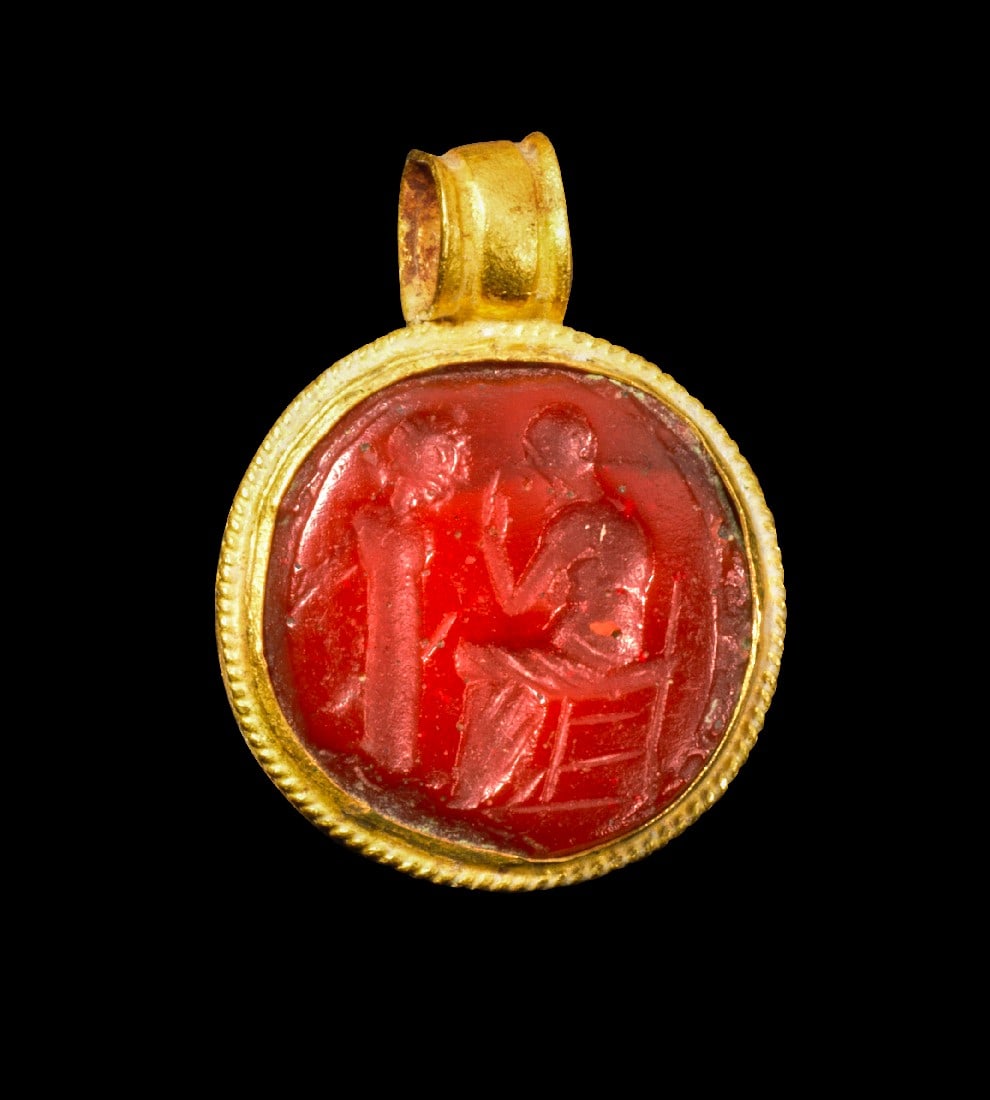 Goldanhänger mit Gemme.: Goldanhänger mit Gemme. Römisch, 2. - 3. Jh. n. Chr. 1,53g, L 1,8cm. In Goldblech gefasste Gemme aus rotem, opakem Glas mit Öse. Auf dem Intaglio thront eine männliche Gestalt vor einer