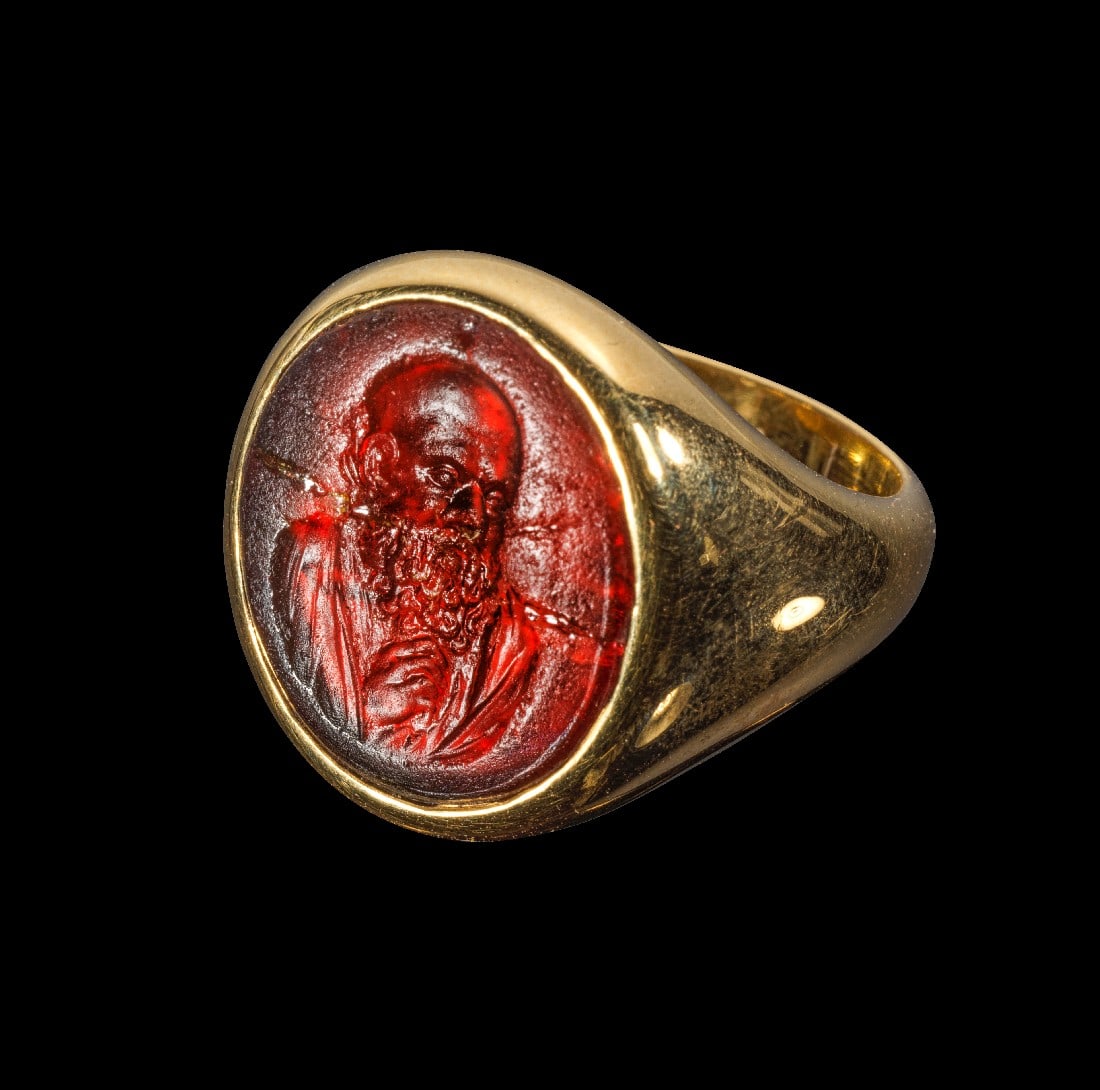 Moderner Goldring mit moderner Glas-Gemme.: Moderner Goldring mit moderner Glas-Gemme. 20. Jh. 20,11g, Ringgröße 56. Schmale, nach oben breiter werdende Schiene mit einer leicht ovalen Fassung. Darin eine hochovale Gemme aus rotem Glas, auf