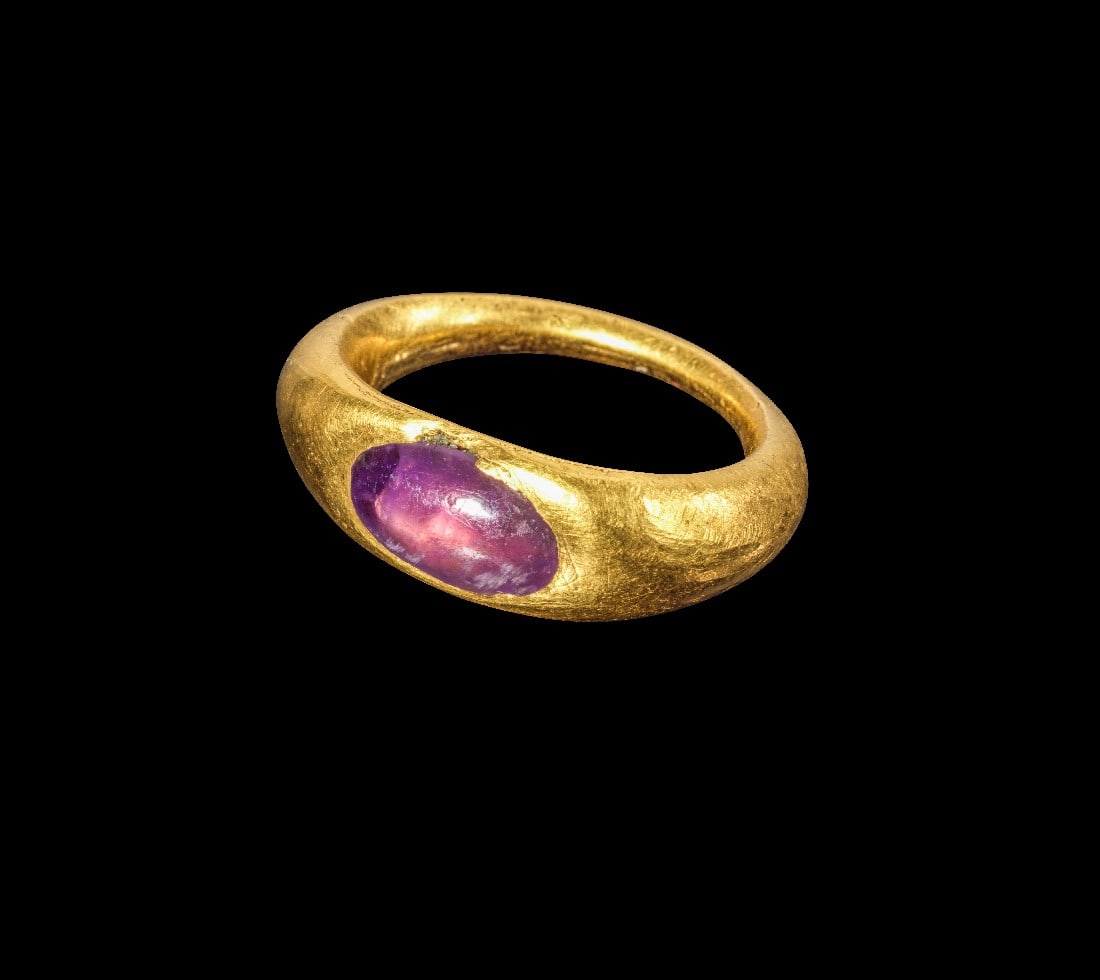 Goldring mit Amethyst.: Goldring mit Amethyst. Römisch, 2. - 3. Jh. n. Chr. 9,58g, Ringgröße 46. Goldring mit nach oben breiter werdender Schiene, auf der Platte eingelassen ein ovaler, gewölbter Ameythst. Gold!