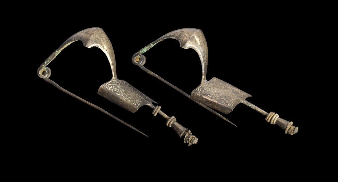 Paar griechische Silberfibeln.: Paar griechische Silberfibeln. Ca. 3. Jh. v. Chr. Bügelfibeln (L 11,8cm) mit rechteckiger Fußplatte, darauf eingravierte Palmetten und Ranken, eine Schmalseite zum Nadelhalter gebogen. Fußplatte