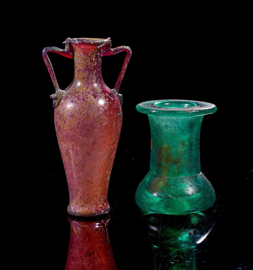 Zwei Gläser.: Zwei Gläser. a) Amphoriskos. Römisch, 1. Jh. n.Chr. H 12,2cm. Aus auberginefarbenem, transluzentem Glas. Frei geblasener Gefäßkörper mit konkavem Boden, zylinderförmigem Hals und