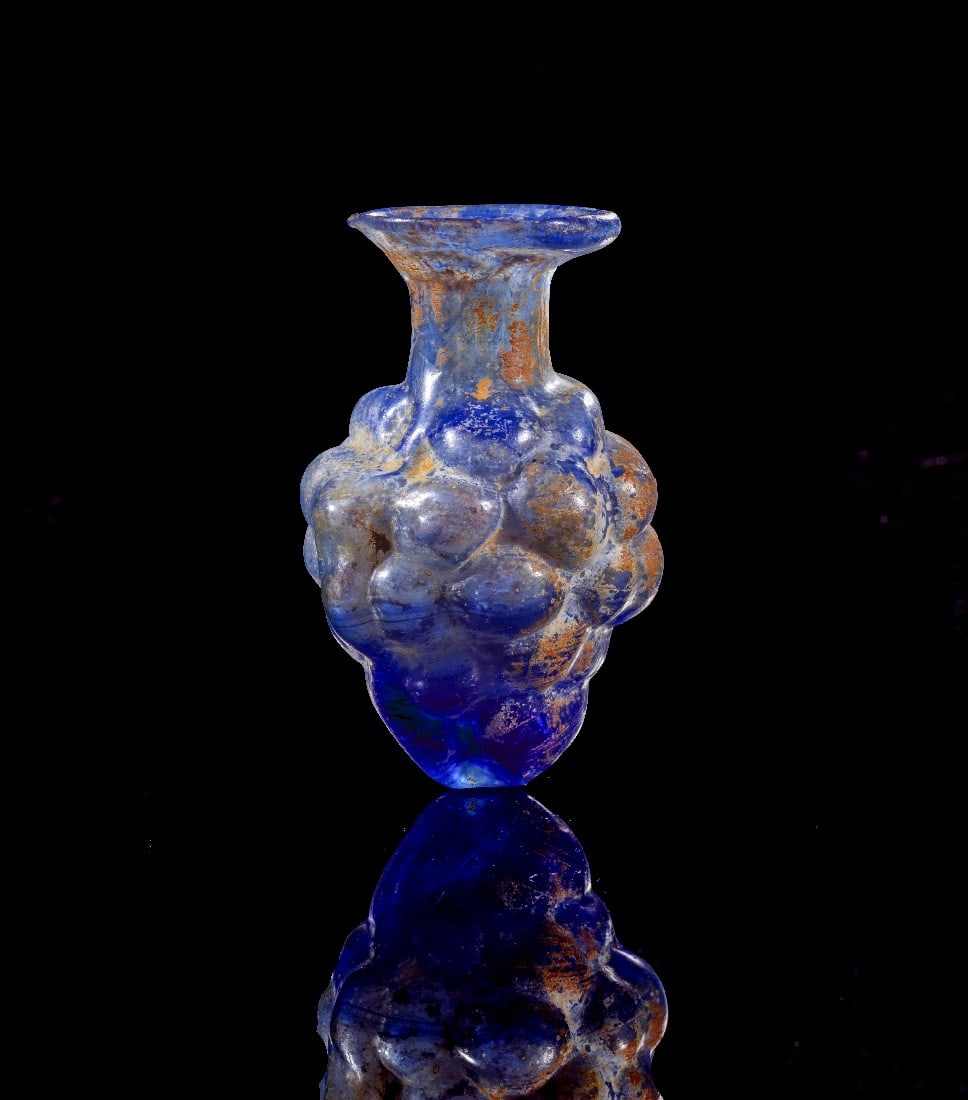 Traubenfläschen.: Traubenfläschen. Römisch, 2. Jh. n. Chr. H 7,5cm. Aus blauem, transluzentem Glas. Formgeblasen aus zweiteiligem Model. Gold! Reste von Sinter, intakt. Provenienz: Ex Sammlung U.K,