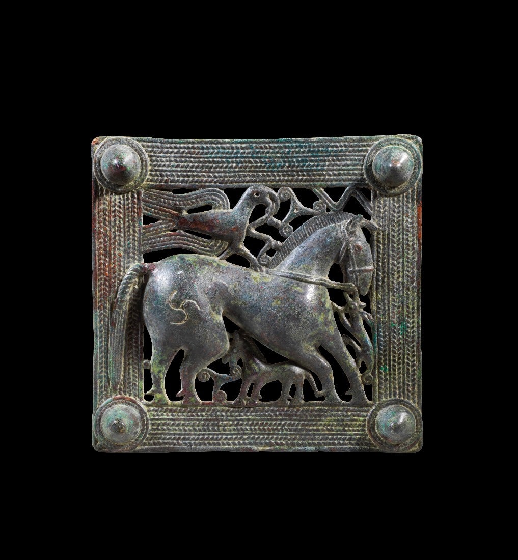 Gürtelschließe mit Tierkampf.: Gürtelschließe mit Tierkampf. Transkaukasien, 1. - 3. Jh. n. Chr. H 12,8 B 13,3cm. Bronzeguss. Quadratisches Relief mit einem Rahmen aus Flechtbändern mit konischen Knubben an den Ecken. Das